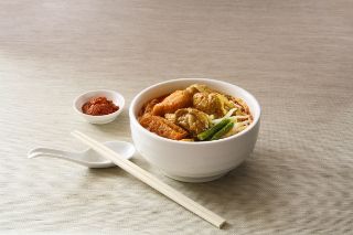 Noodle soup in bowl with sticks and spices